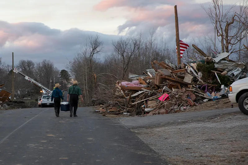 An Amish father and son off food and drinks as they walk through a tornado destroyed subdivision in Kentucky.